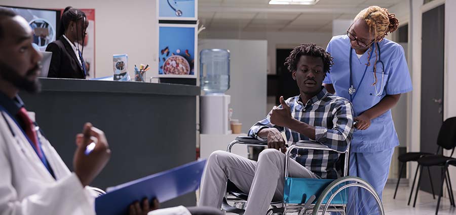 black-caregiver-woman-helping-an-impaired-young-man-on-a-wheel-chair.Hand-on training at Paula training institute.