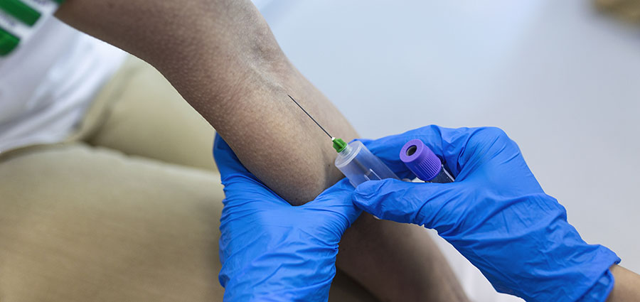 Medical technologist doing a blood draw services for patient. lab assistant with sterile rubber gloves taking blood sample from patient.